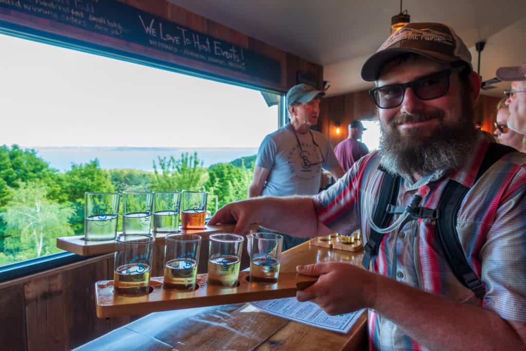 bike-n-ride traverse city Barrett holding a cider flight at Suttons Bay Ciders on the Traverse City area DIY bike-n-ride tour