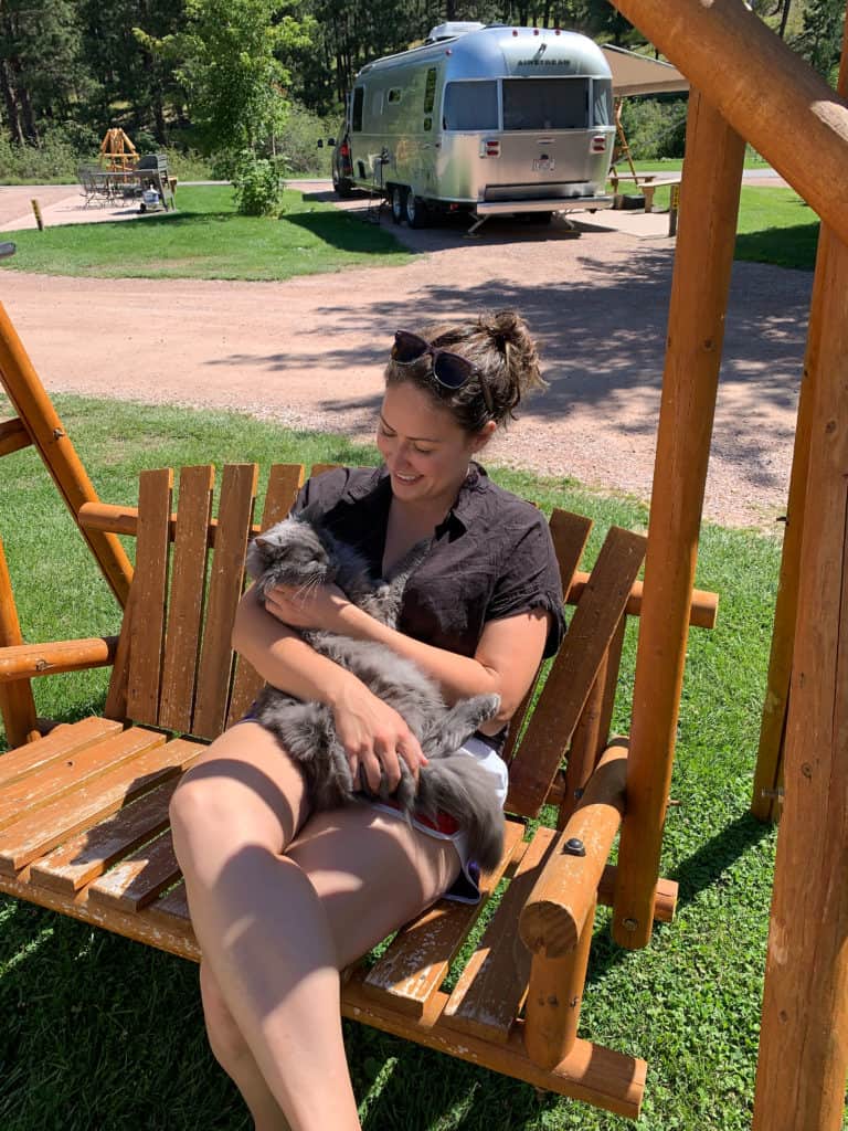 best rv parks Cindy on swinging bench with cat at the Mount Rushmore KOA at Palmer Gulch Resort